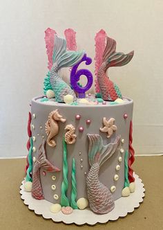 a birthday cake decorated with seahorses and mermaid tails