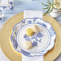 two macaroons on a blue and white plate next to a vase with flowers