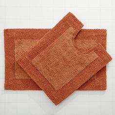 two orange bath mats sitting next to each other