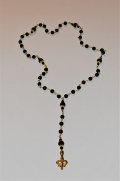 Gold plated fleur de lis on 7mm matte black onyx bead chain accented with 3mm gold plated bead and 4mm matte black onyx with gold plated filigree capped 8mm matte black onyx. Dimensions: 24 inches necklace, total length with drop 34 inches fleur de lis pendant measures 2.5 inches Handcrafted in New Orleans by Studio 25. Elegant Black Jewelry With 8mm Beads, Elegant Matte Black Adjustable Jewelry, Elegant Adjustable Matte Black Jewelry, Elegant Black Beaded Chain Jewelry, Formal Black Necklace With Beaded Chain, Formal Black Jewelry With Gold Beads, Black Jewelry With Gold Beads For Formal Occasions, Matte Black Elegant Jewelry For Formal Occasions, Elegant Matte Black Jewelry For Formal Occasions