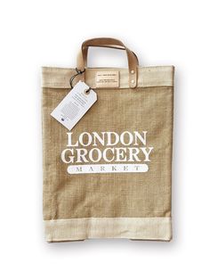 the london grocery market tote bag is hanging from a hook on a white wall