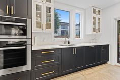 a kitchen with black and white cabinets, gold trimmings and stainless steel appliances