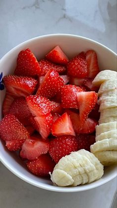 a white bowl filled with sliced bananas and strawberries