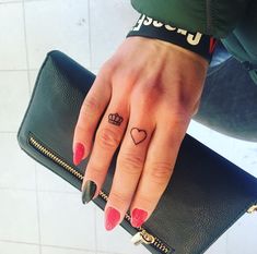 a woman's hand with a heart and crown tattoo on her left ring finger