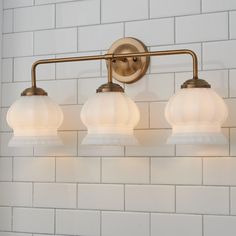 three light bathroom fixture with glass shades on white brick wallpapered walls and floor