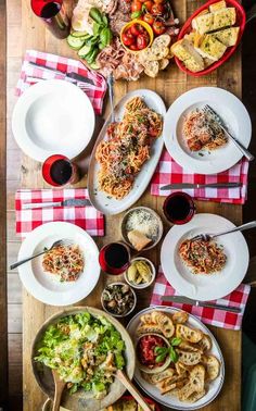 a wooden table topped with lots of plates and bowls filled with different types of food