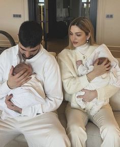 a man holding a baby while sitting next to a woman