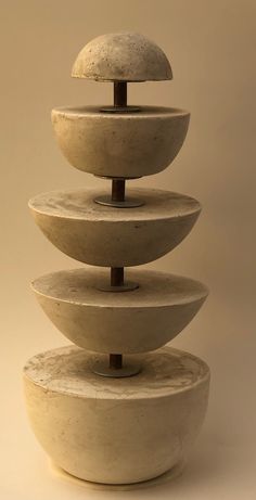 a stack of white bowls sitting on top of each other in front of a beige wall