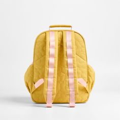 A backpack that's extra comfy and ready to handle all the adventures of the day. A pattern of quilted blooms add sunny vibes to the bag's yellow exterior, and contrasting pink trim gives it the perfect finish. Constructed of supremely durable polyester fabric that includes recycled plastic bottles, this medium knapsack's roomy interior holds everything your kid needs-books, school supplies, extra layers-and there's a padded pocket to keep their tablet protected. Outside pockets hold snacks, wate Cute Yellow Backpack For Students, Cute Yellow School Backpack, Playful Yellow Bags For Back To School, Quilted Backpack For Back To School, Cute Yellow Backpack For Back To School, Quilted Standard Backpack For Back To School, Back To School Quilted Backpack, Quilted Backpack For Travel And Back To School, Playful Yellow Backpack For Back To School