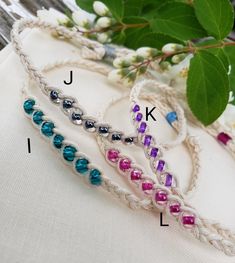 three bracelets with different colored beads are on top of a white cloth next to flowers