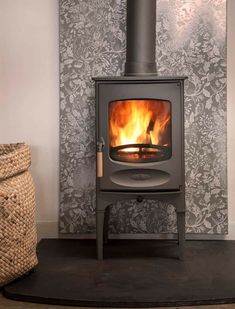 a wood burning stove sitting next to a wall with a basket on the floor in front of it