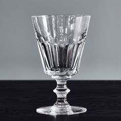 a clear glass sitting on top of a wooden table next to a gray wall in the background