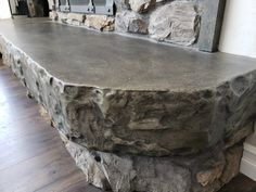 a large stone bench sitting in front of a brick wall on top of a hard wood floor