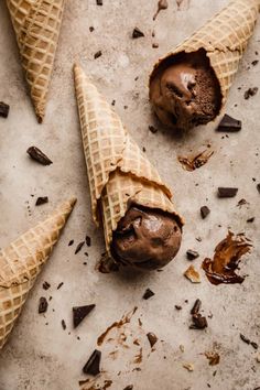 three ice cream cones with chocolate filling on a white surface, one is broken in half