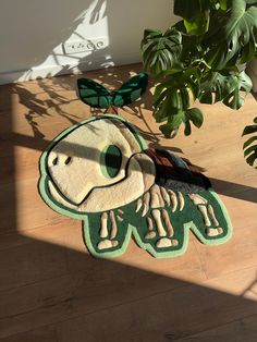 a green and white rug sitting on top of a wooden floor next to a potted plant