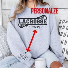 This Lacrosse sweatshirt is the perfect gift for the proud Lacrosse Mom. What makes it truly special is the ability to personalize it with your child's name and number, proudly displayed on the outside/right sleeve. Whether it's for game days or just showing off your team spirit around town, this sweatshirt is sure to make a statement. INTERESTED IN OTHER LACROSSE PRODUCTS? VISIT HERE: https://www.etsy.com/shop/MomsNextAdventure?section_id=34481331 ⭐️INFORMATION ABOUT THE GILDAN UNISEX SWEATSHIRT⭐️ ✓ Medium-Heavy Fabric  ✓ 50% cotton, 50% polyester and they are super comfortable and soft! ✓ Fabric blends: Heather Sport colors - 60% polyester, 40% cotton ✓ Classic fit / Runs true to size. Refer to size chart. ✓ Order the size you would normally order if you want a super comfy, slightly loos Lacrosse Gifts, Bonus Mom, Personalized Gifts For Mom, Mom Sweatshirt, Lacrosse, Mom Shirt