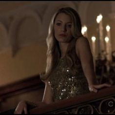 a beautiful blonde woman standing on top of a stair case in a room with candles