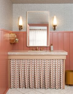 a bathroom with pink walls and tile flooring, two lights on the wall and a mirror above the sink