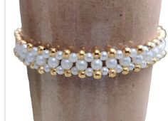 a close up of a person's leg wearing gold and white beaded bracelets