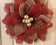 a red and green wreath on the front door with two gold balls hanging from it