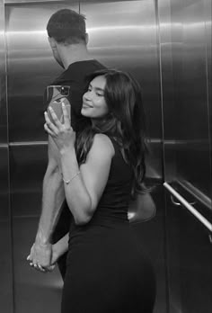 black and white photograph of a man hugging a woman in front of an escalator