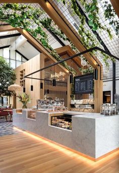 the interior of a restaurant with wooden floors and plants growing on the wall above it