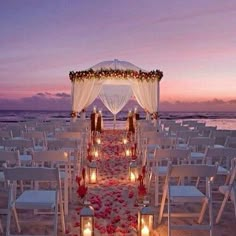 an outdoor wedding setup with candles and flowers on the beach