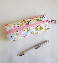 a pen and pencil case sitting next to each other on a white surface with a flower pattern