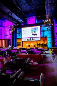 a large room filled with lots of purple couches and chandelier hanging from the ceiling