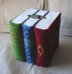 two crocheted books sitting on top of a white couch next to each other