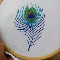 a peacock feather is embroidered onto a white cloth