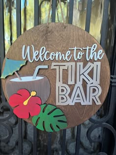 a wooden sign that says welcome to the tiki bar with a flower on it