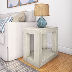 a white couch sitting next to a table with a blue vase on top of it