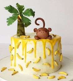 a cake decorated with bananas and a monkey on top is sitting next to a banana tree