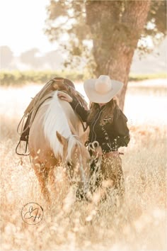 a cowboy kissing a horse in the middle of a field with tall grass and trees