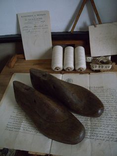 two wooden shoes are on top of an old book next to some rolls of paper