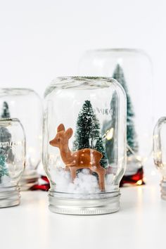 glass jars filled with miniature christmas trees and deer figurines