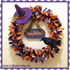 a purple and orange halloween wreath with a black bird on it, hanging from the wall