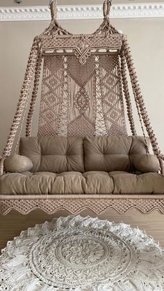 a white crocheted bed hanging from the ceiling next to a round doily rug