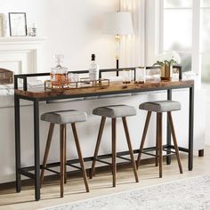 a bar with stools and bottles on it in front of a window next to a couch