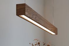 a wooden light fixture hanging from a ceiling in a room with white walls and plants