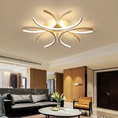 a living room with couches, tables and lamps on the ceiling is lit by modern lighting fixtures