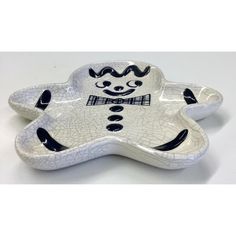 a white and black ceramic dish with a clown face on it's back side