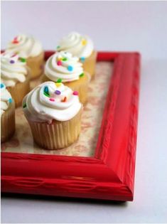 there are pictures of cupcakes on the table and in front of it is an empty frame