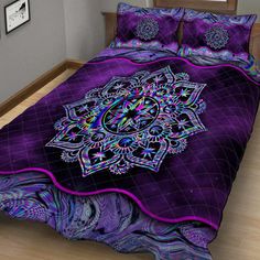 a bed covered in purple and black bedspread with an intricate design on it