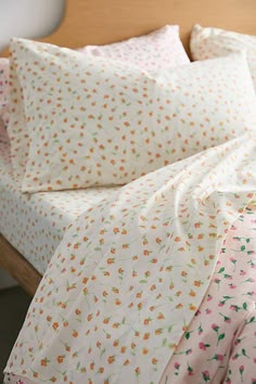 an unmade bed with floral sheets and pillows