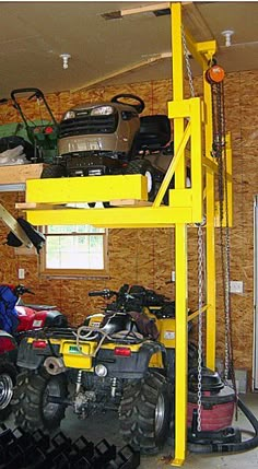 there is a yellow lift in the garage with two atvs on top of it