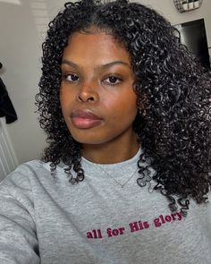 a woman with curly hair wearing a grey shirt