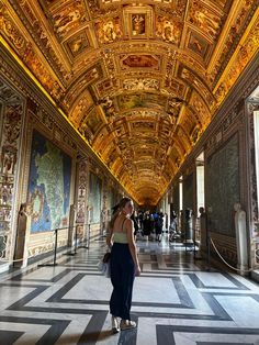 a woman is standing in the middle of a hall with many paintings on the walls