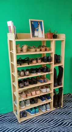 there is a shoe rack with many pairs of shoes on it in front of a green wall